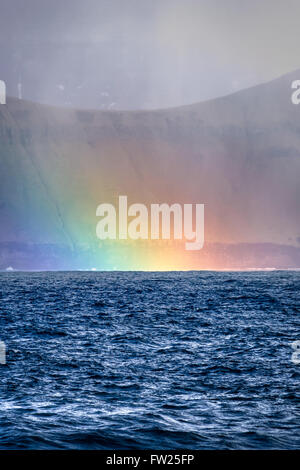 Giant sea cliffs shortly after storm on Faroe Islands with a rainbow. Stock Photo