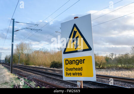 Danger overhead live wires sign next to train tracks Stock Photo