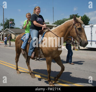 Americus, Kansas, USA, 14th June, 2014 Two girls riding double on their horse during the parade  The Annual Americus Days parade takes place on the 3 blocks of Main St.  Americus is a city in Lyon County, Kansas, United States. As of the 2010 census, the city population was 896. It is part of the Emporia Micropolitan Statistical Area. Credit: Mark Reinstein Stock Photo