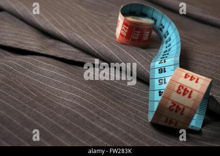 Measure tape being unrolled on top of a classic striped suit coat Stock Photo