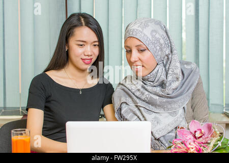 Asian and muslim girls working together on a laptop Stock Photo