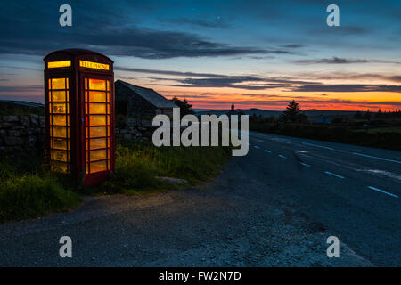 Iconic red phone booth in English countryside at night Stock Photo