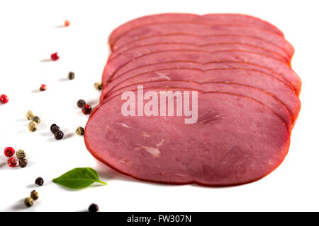 Fresh sliced beef pastrami surrounded by herbs over white background Stock Photo