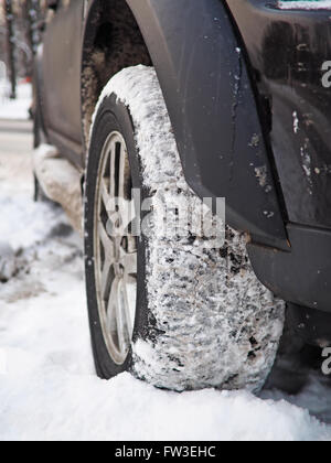 SUV in snow close-up of snowy tire. Shallow depth of field Stock Photo