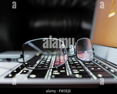Reading eyeglasses on an elegance laptop keyboard, shallow depth of field Stock Photo