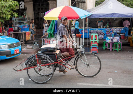 YANGON, MYANMAR - JANUARY 3, 2016: Unidentified man riding a trishaw on the streets of Yangon , Myanmar on January 3, 2016 Stock Photo