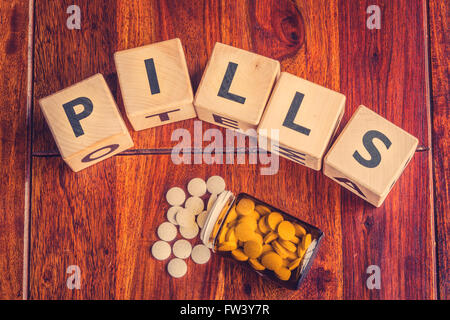 The word pills on a dark wooden table Stock Photo
