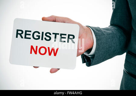 closeup of a young caucasian man in a gray suit showing a signboard with the text register now Stock Photo