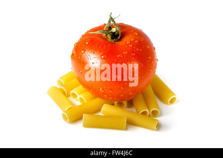 Fresh tomato standing on raw uncooked macaroni isolated on white background Stock Photo
