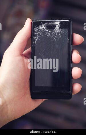 Woman holding broken smartphone in her hand. Smartphone with cracked screen. Close up. Stock Photo