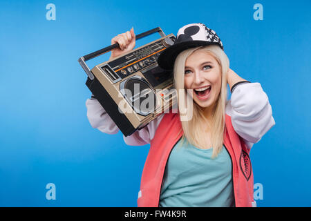 Cheerful young woman holding retro boom box on blue background Stock Photo