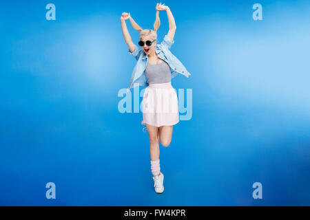 Full length portrait cheerful styish woman posing over blue background Stock Photo