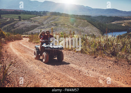 Young couple having fun in the countryside while driving on a quad bike. Young man and woman enjoying off road vehicle ride on a Stock Photo