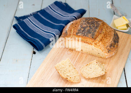 Loaf of freshly baked sliced homemade Struan bread, on a rustic blue table. Stock Photo