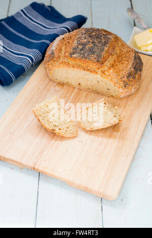 Loaf of freshly baked sliced homemade Struan bread, on a rustic blue table. Stock Photo