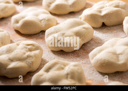Fresh loaves of bread with specialist shapes laid out on a floured wooden bakery table, close up view with selective focus Stock Photo