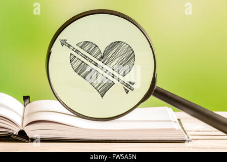 Love search with a pencil drawing of a heart with an arrow in a magnifying glass Stock Photo