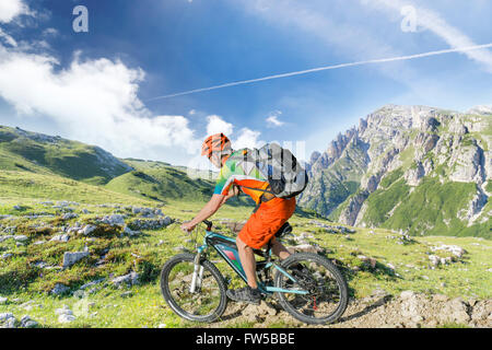 E bike traveler with backpack rides a mountain trail Stock Photo