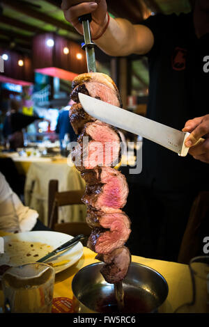 Picanha, traditional Brazilian barbecue sliced directly at the restaurant table. Stock Photo