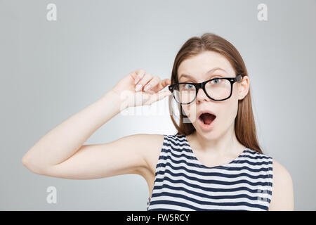 Portrait of amazed charming teenage girl in glasses and striped clothes with mouth opened over Stock Photo