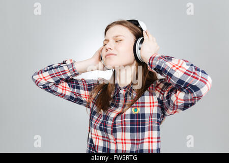 Cute lovely teenage girl in plaid shirt listening to music in headphones Stock Photo