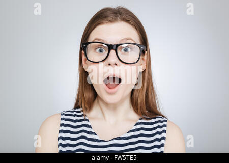 Portrait of pretty teenage girl in glasses with mouth opened over gray Stock Photo