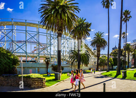 Young girls strolling through City park, on a hot summers day, near Luna Park,  St Kilda, Melbourne Australia Stock Photo