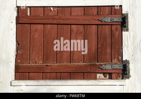 Old weathered window shutter made of red planks Stock Photo