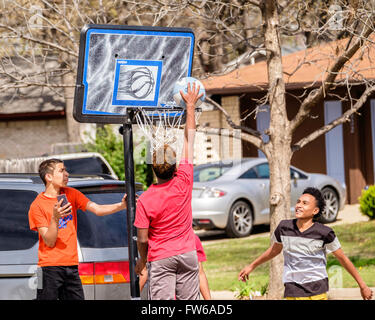 Teen and pre-teen boys gather and play basketball on the street in Oklahoma City, Oklahoma, USA. Stock Photo