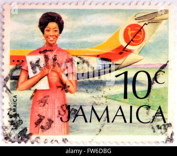JAMAICA - CIRCA 1972: Stamp printed in Jamaica shows A Flight Attendant Standing In Front Of An Air Jamaica Airplane, circa 1972 Stock Photo