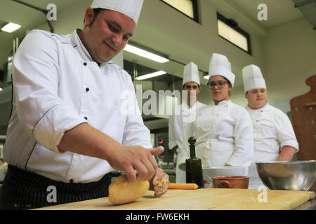 A chef making fresh pasta in kitchen with apprentices in the background,Gubbio,Umbria,Italy Stock Photo