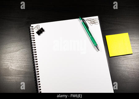 Notebook with blank paper, color sticky notes, pen and clips on a wooden table Stock Photo