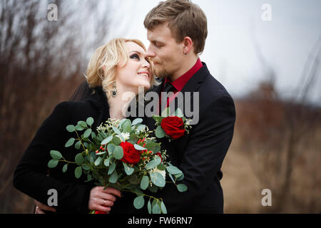 Happy hugging wedding couple with bouquet in the wood Stock Photo