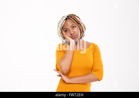 Sad bored african american young woman in yellow dress standing over white background Stock Photo