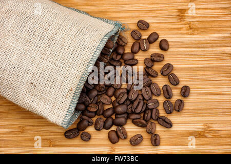 Coffee beans spilling out of burlap bag. Close up. Stock Photo