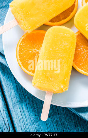 overhead view, orange natural juice popsicle on blue plate Stock Photo