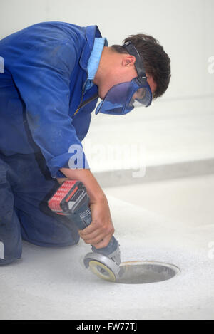 A builder grinds a smooth edge around a drain before a floor laying job begins Stock Photo