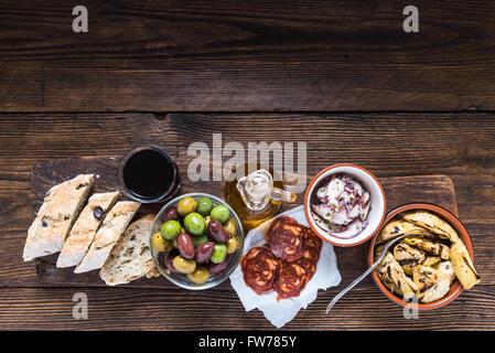 Wooden board with tapas, olives and salami and olive oil, from above, copy space for text or advert. Stock Photo