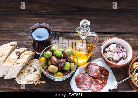 Wooden board with tapas, olives and salami and olive oil, from above, copy space for text or advert. Stock Photo