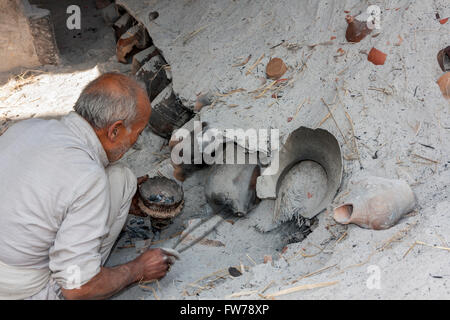 Bhaktapur, Nepal.  Potter at Work Tending his Kiln in Potters' Square. Stock Photo
