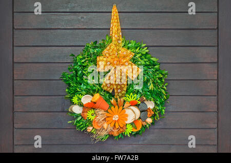 Spring wreath with orange bow hanging on dark wooden door Stock Photo