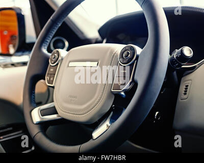 Luxury SUV Interior: Multifunctional steering wheel with control buttons and dashboard, shallow depth of field Stock Photo