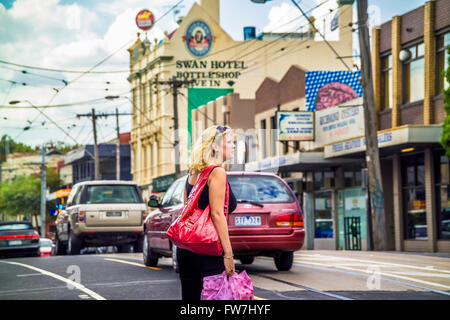 Woman crossing busy street,  inner city life, Swan Street, Richmond, Melbourne Australia Stock Photo