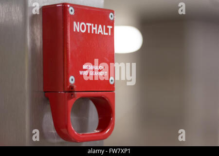 Red emergency brake marked with german words "Nothalt Missbrauch Strafbar" Stock Photo