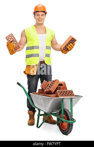 Construction worker holding bricks behind a wheelbarrow isolated on white background Stock Photo