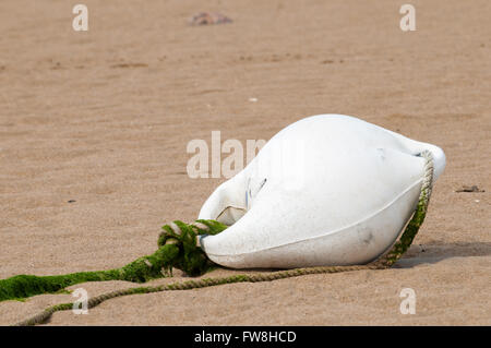 White buoy lying in the yellow sand of a beach Stock Photo