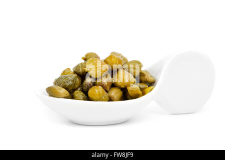 some pickled capers in a white porcelain spoon, on a white background Stock Photo