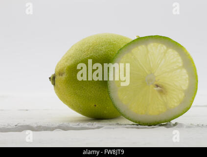 Close up of whole lemon an slice isolated on rustic white wood background Stock Photo