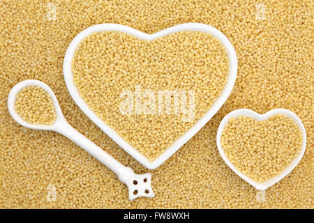 Pearl couscous food in heart shaped bowls and porcelain spoon forming an abstract background. Stock Photo