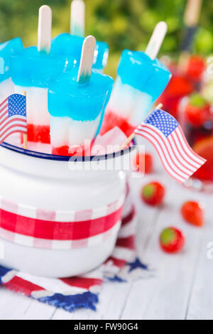 Homemade red-white-and-blue popsicles on an outdoor table with refreshing lemonade in the background. Stock Photo